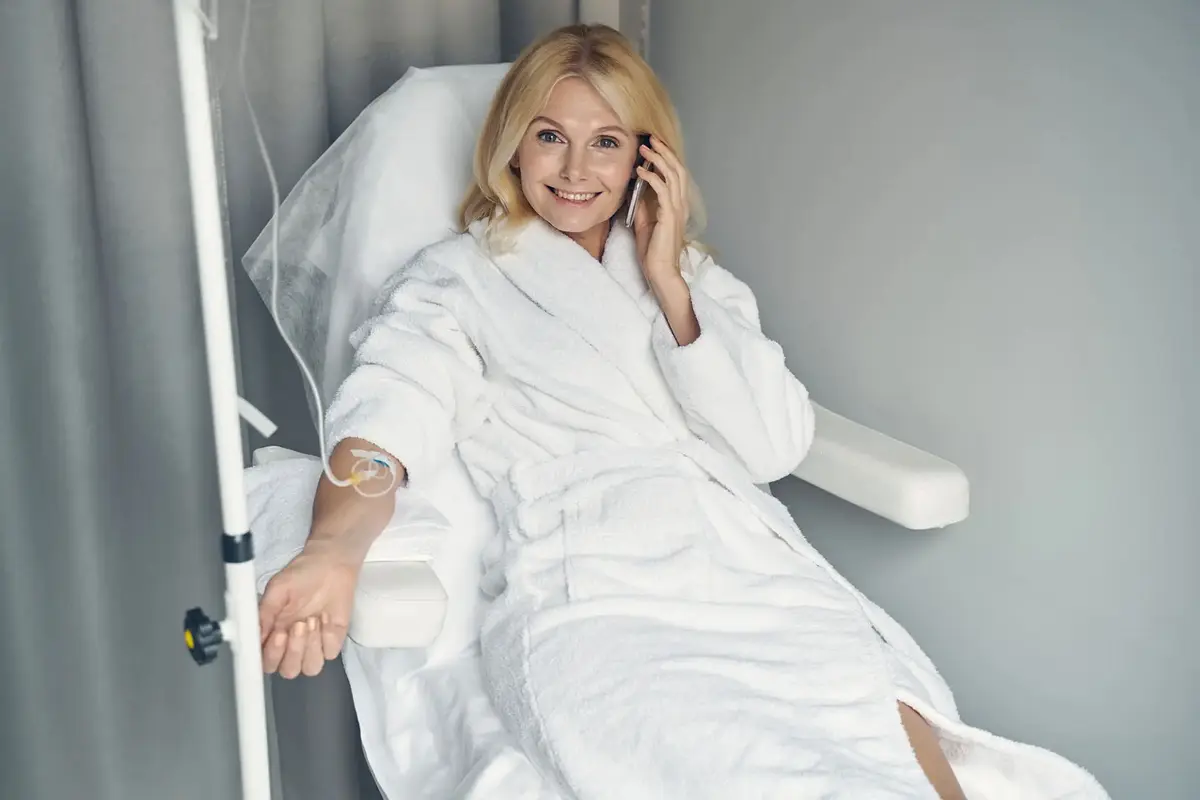 Woman in a white robe talking on the phone and donating blood.