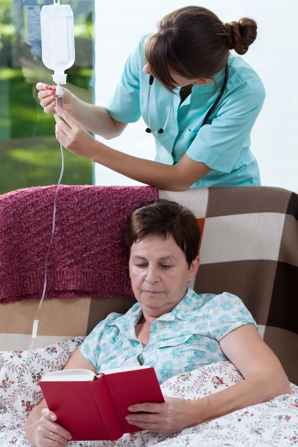 A nurse giving an IV drip to a seated patient.