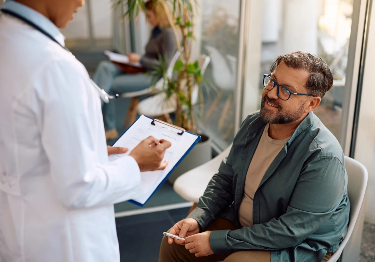 Doctor consulting with seated patient in clinic.