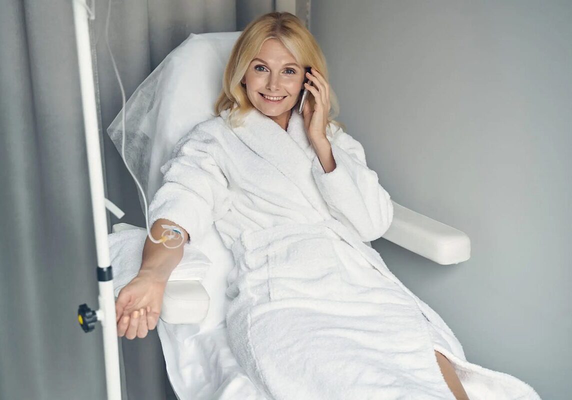 Woman in a white robe talking on the phone and donating blood.